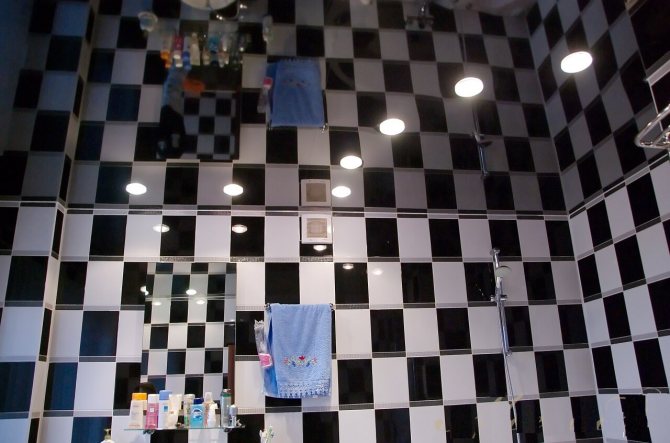 Сочетание зеркального потолка и отделки стен ванной в черно-белых тонах
